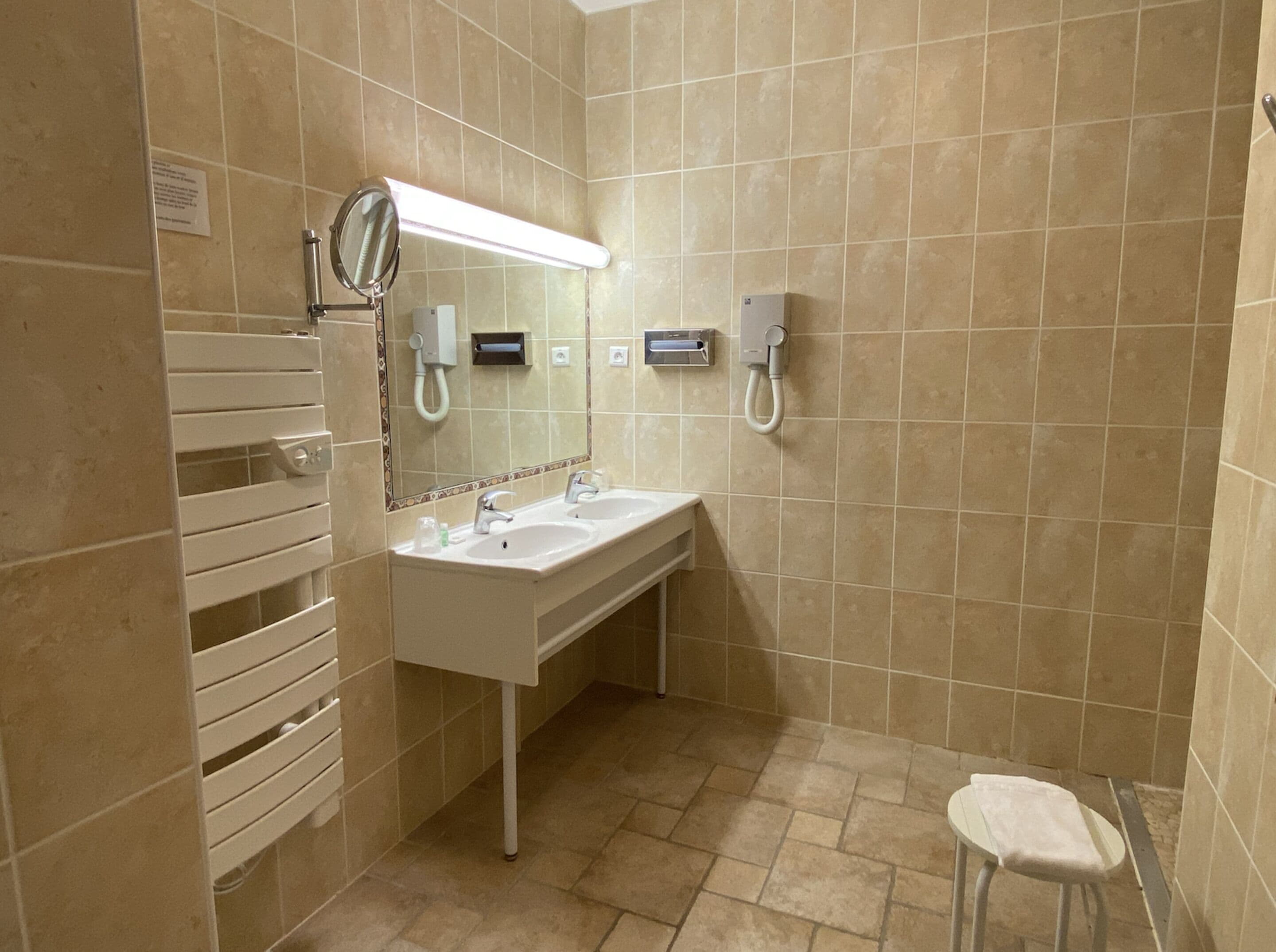 A bathroom with two sinks, a mirror, a towel rack, and a toilet.
