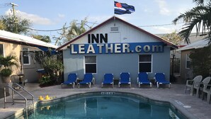 Un área de piscina al aire libre con sillones de descanso y un edificio con la inscripción "INN LEATHER.com".