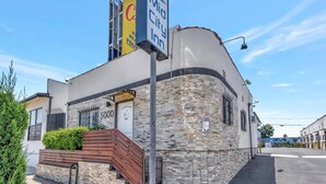 A building with a stone facade, a sign for 'Mid City Inn', and a staircase leading to the entrance. - Mid City inn (Los Angeles)