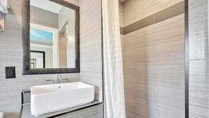 A modern bathroom with a white sink, a large mirror, and a shower curtain. - Mid City inn (Los Angeles)