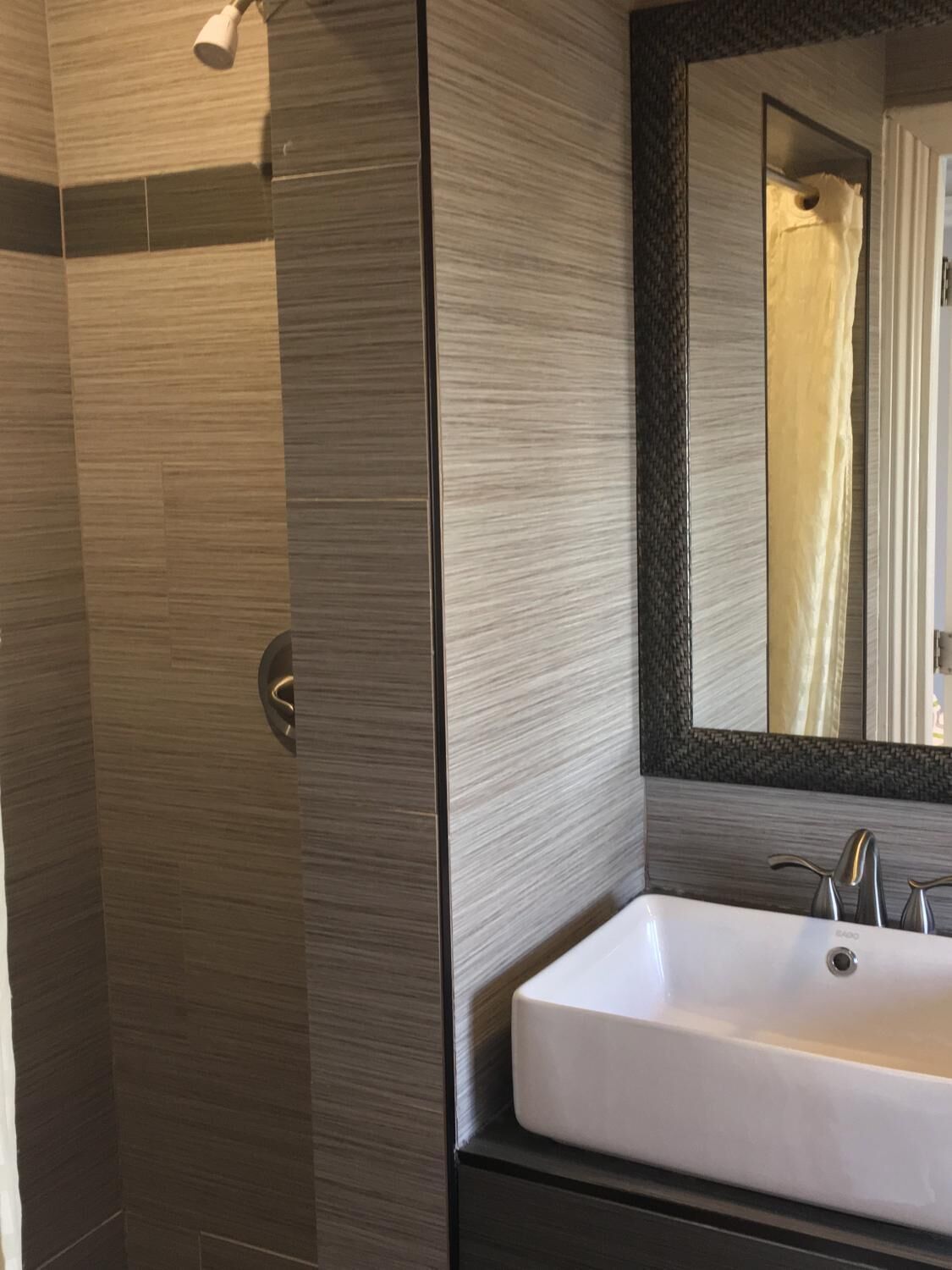 Une salle de bain moderne avec un grand miroir, un lavabo blanc et un espace douche.