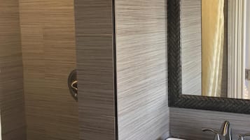 Une salle de bain moderne avec un grand miroir, un lavabo blanc et un espace douche.