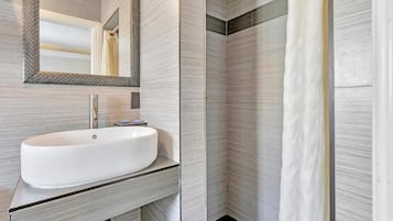 Een moderne badkamer met een grote witte wastafel, een spiegel en een douchegordijn.