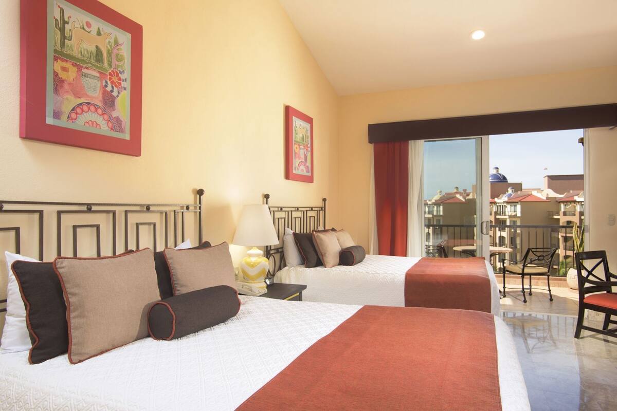 Une chambre d’hôtel avec deux lits, un balcon et une vue sur les immeubles.
