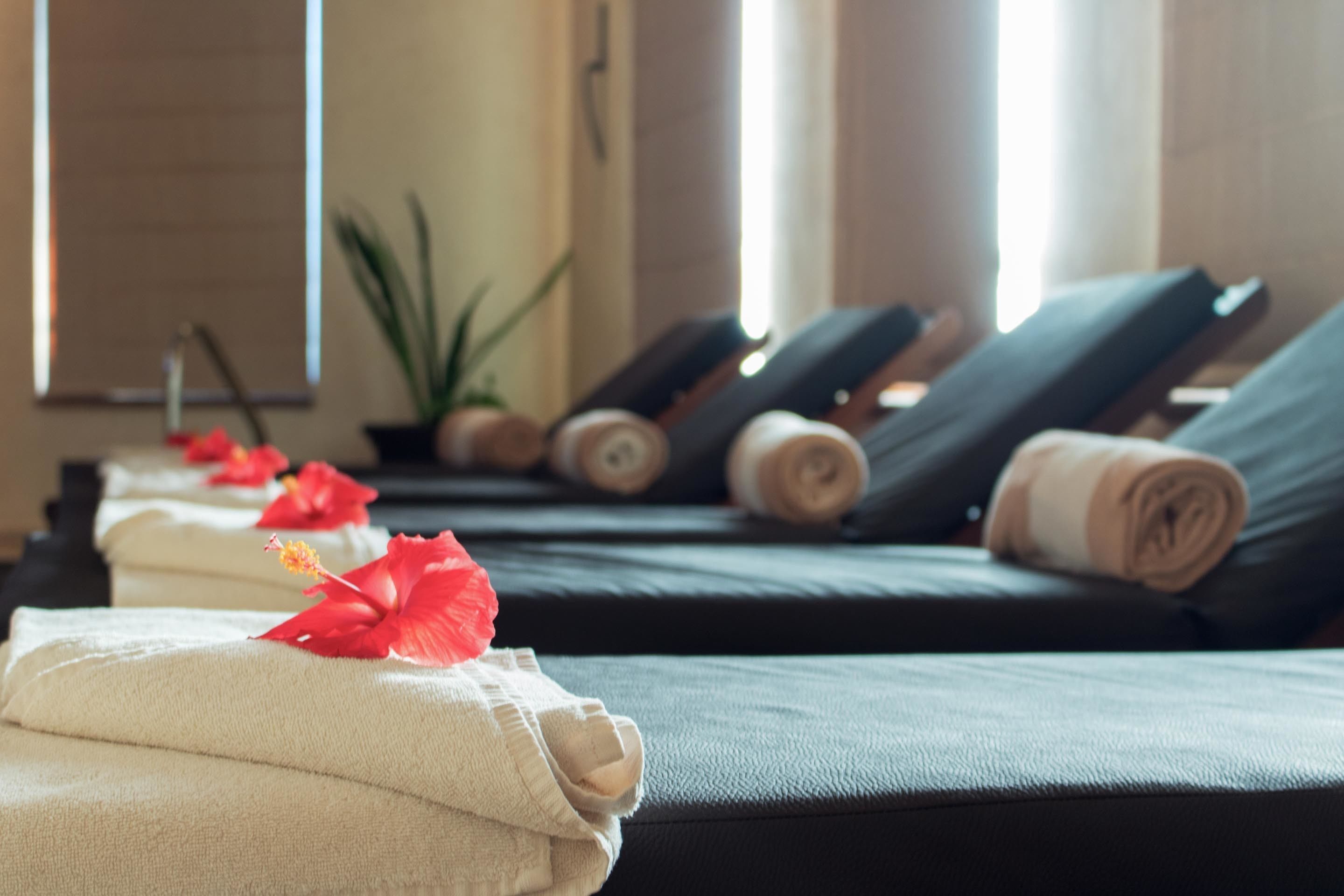 A spa room with massage tables, towels, and decorative flowers.