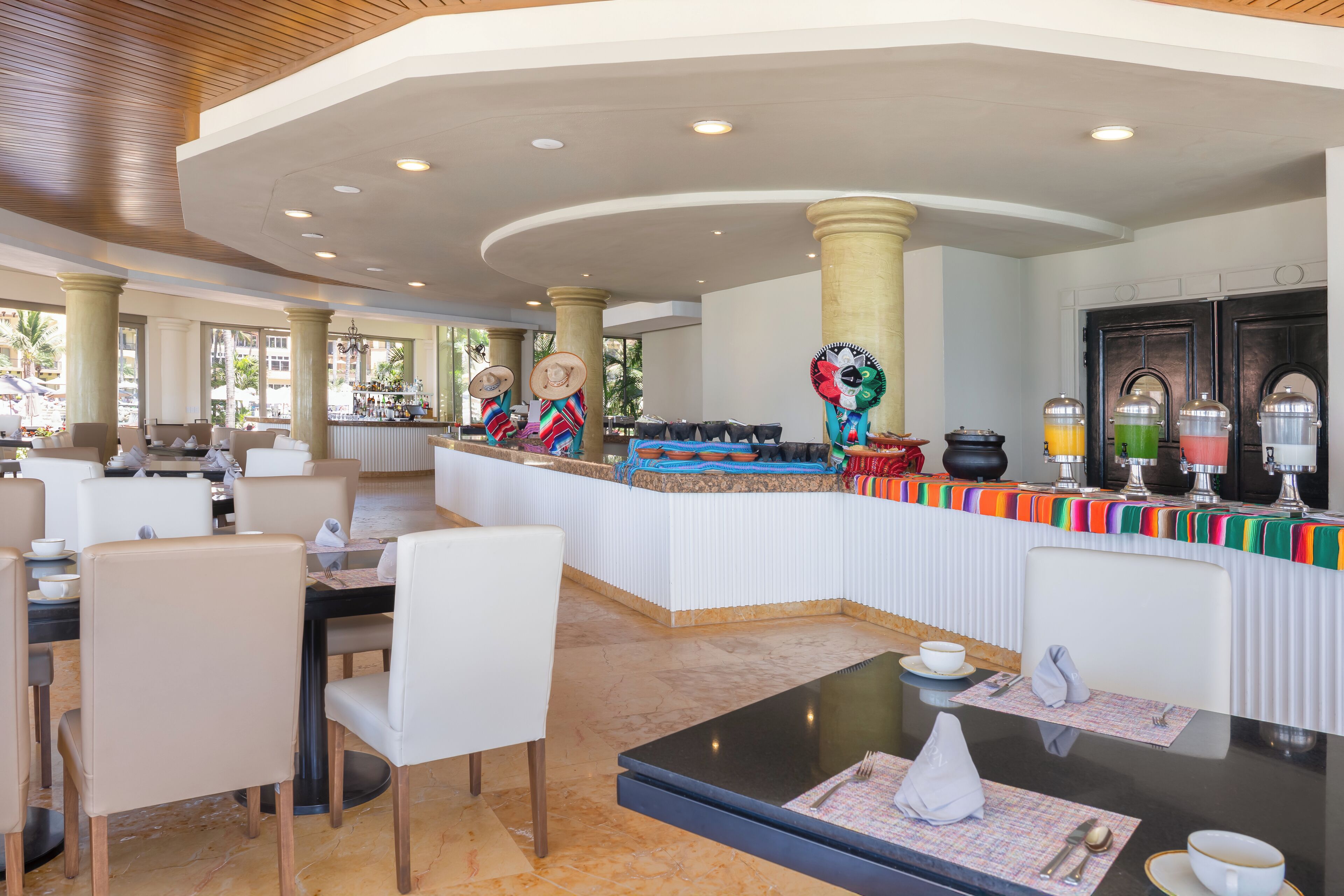 A spacious lobby with a central bar area, comfortable seating, and a view of the outdoors.