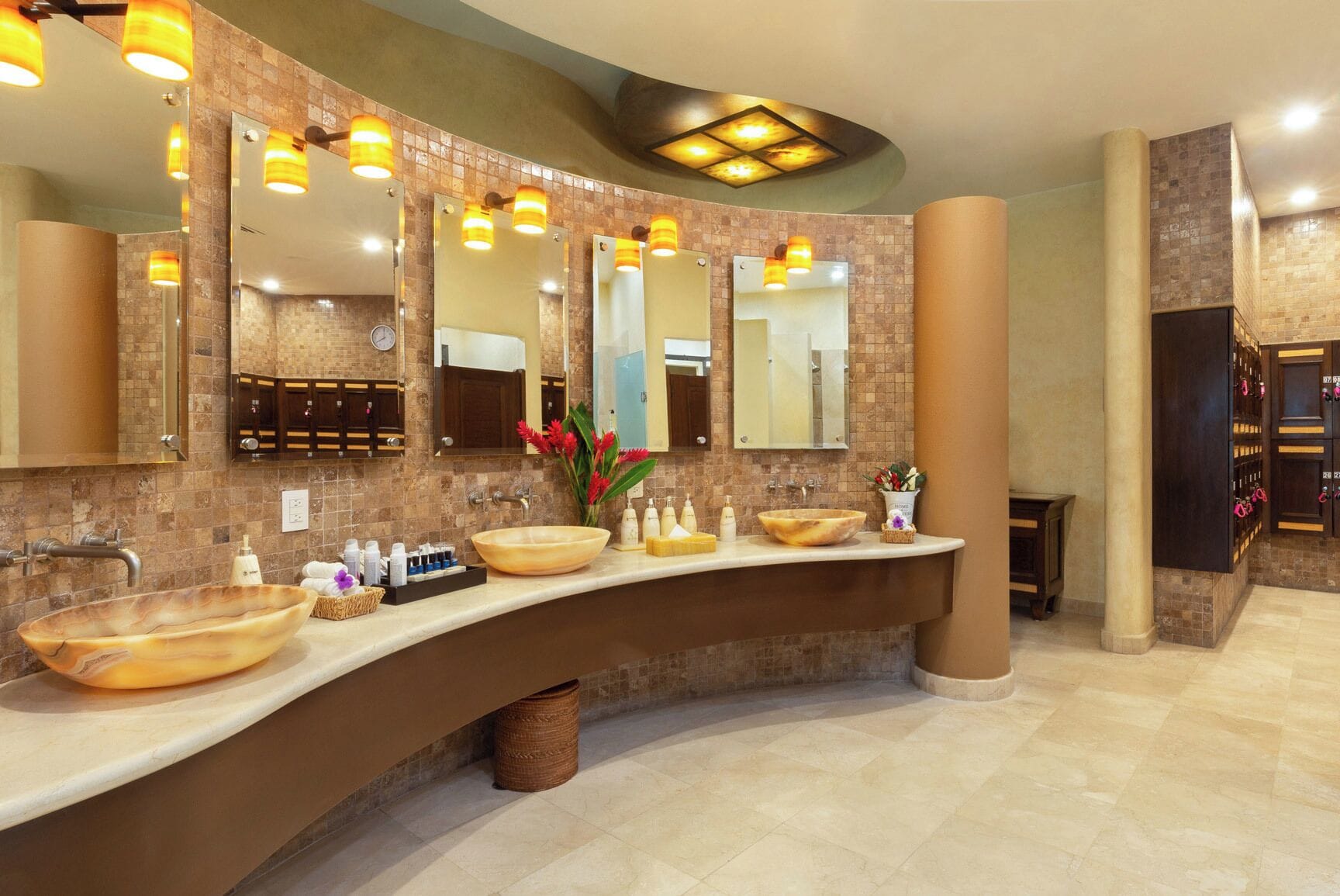A modern bathroom with two large vessel sinks, a mirror, and a vanity area with toiletries.