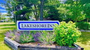 A sign for Lakeshore Inn surrounded by a landscaped garden with various plants. - Elk Rapids Lakeshore Inn (Williamsburg)