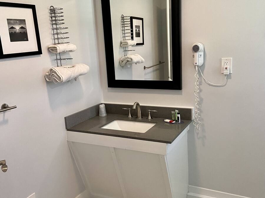 Une salle de bain équipée d’un lavabo, d’un miroir, d’un porte-serviettes et d’un sèche-cheveux.