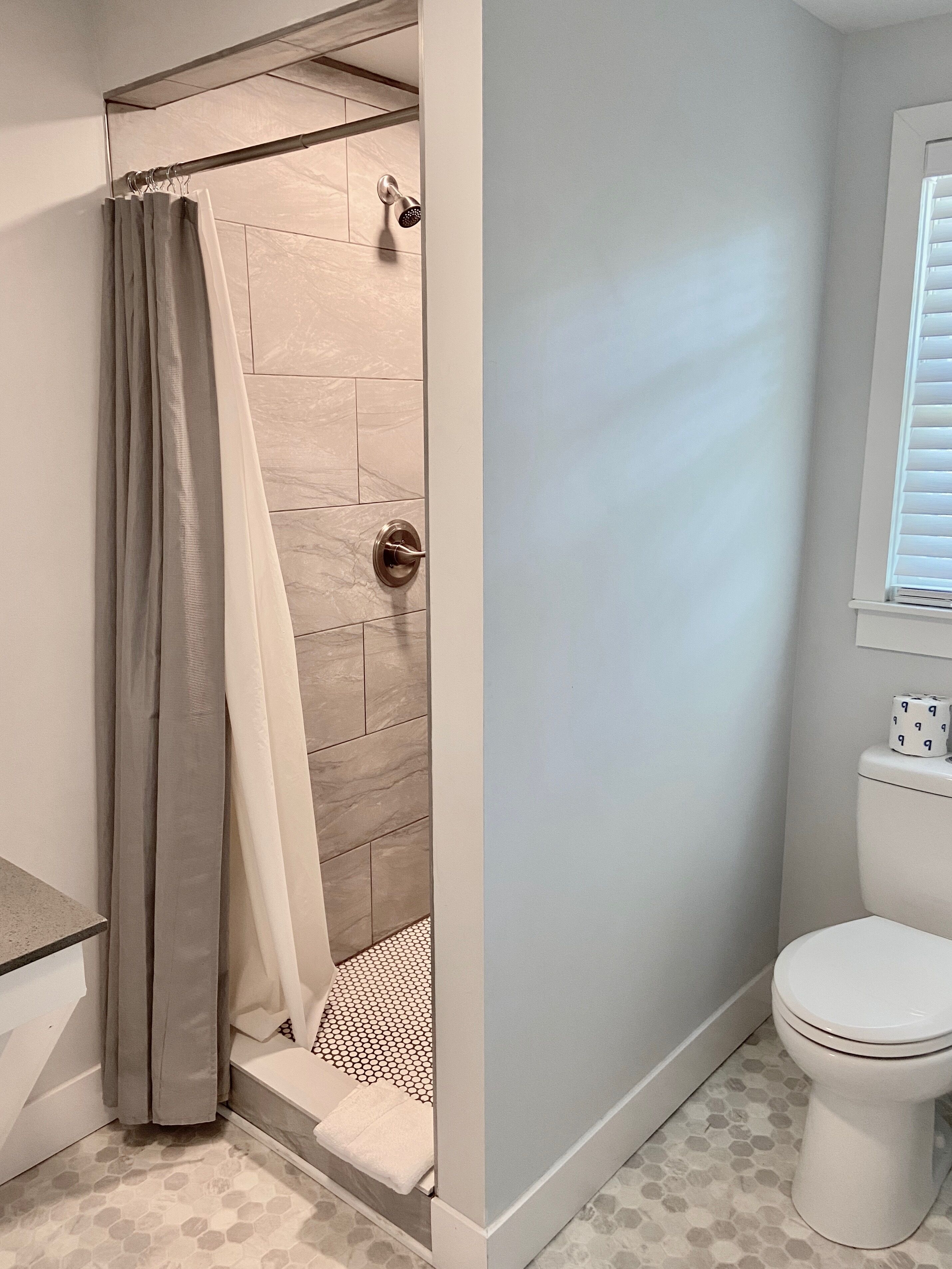 Une salle de bain avec une douche, des toilettes et un porte-serviettes.