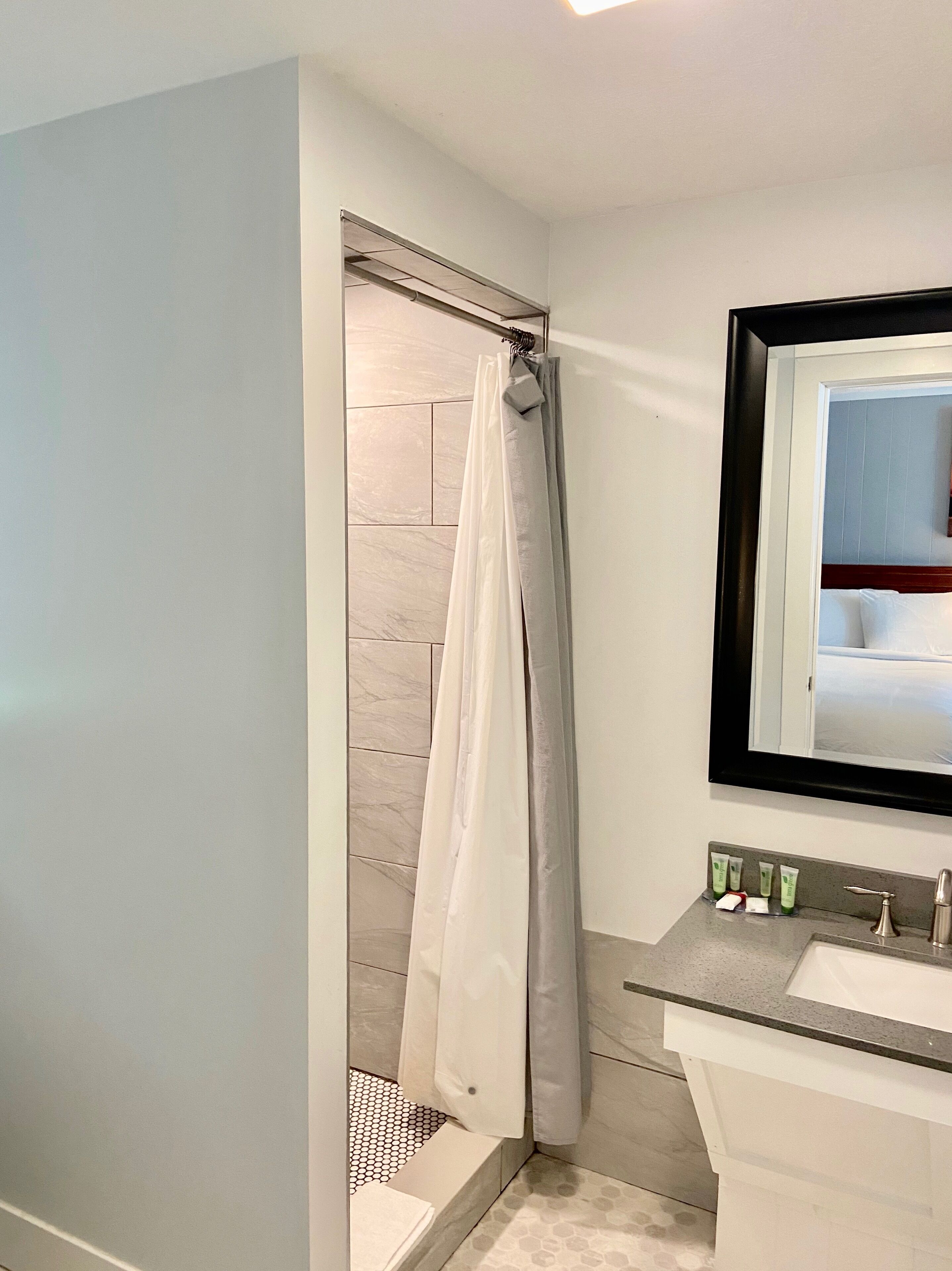 Ein Badezimmer mit Duschvorhang, Waschbecken und Spiegel.