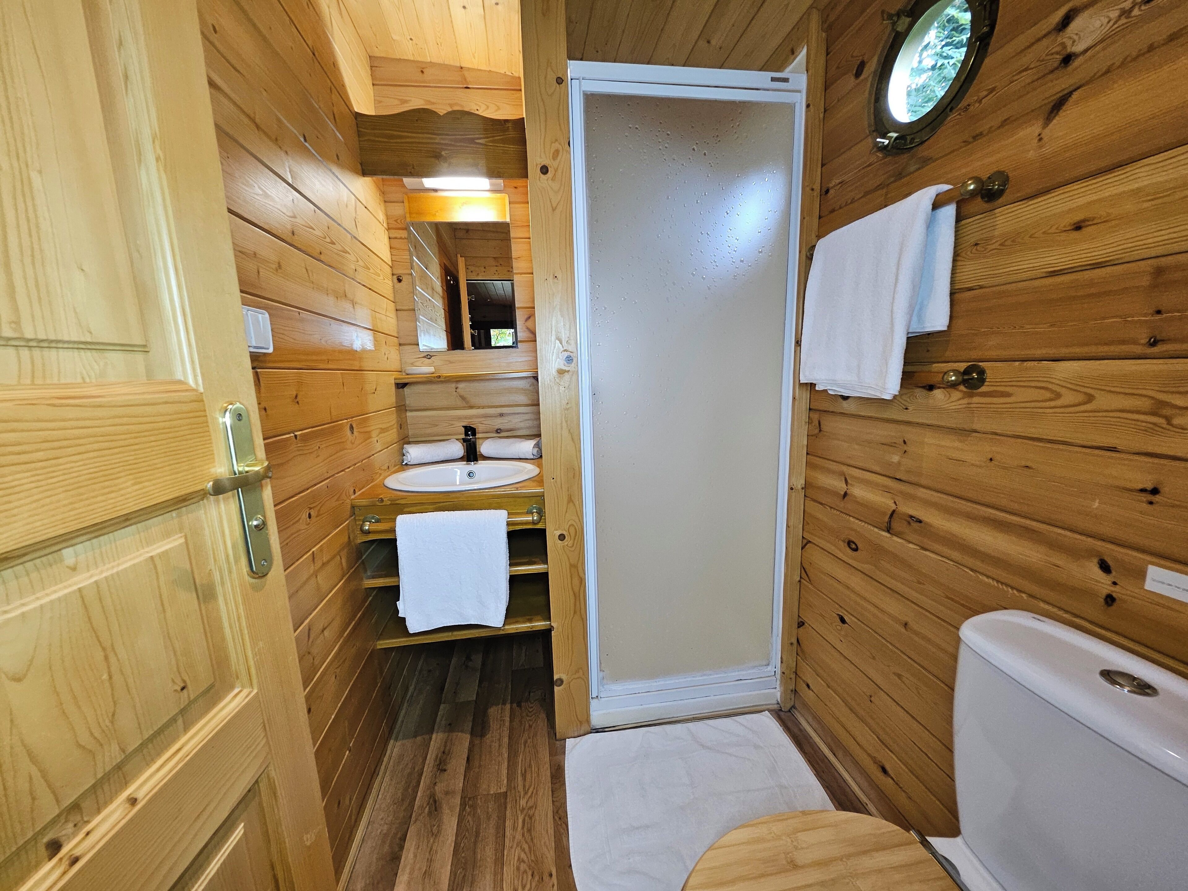 A wooden cabin bathroom with a sink, toilet, and a mirror above the sink.