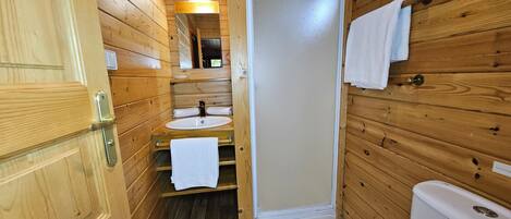 A wooden cabin bathroom with a sink, toilet, and a mirror above the sink.
