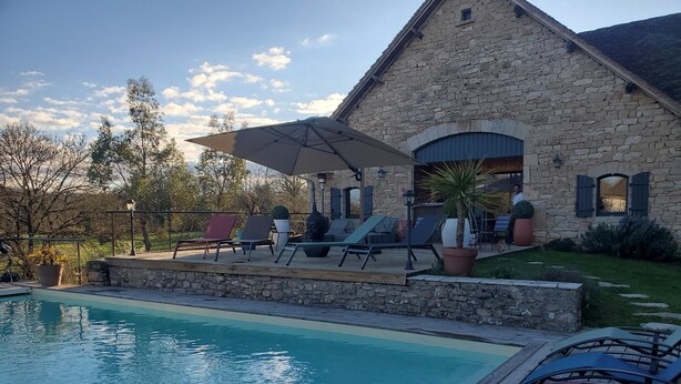 A stone building with a pool, lounge chairs, and a covered patio area. - Roulottes du Petit Gouffre de Padirac (Padirac)