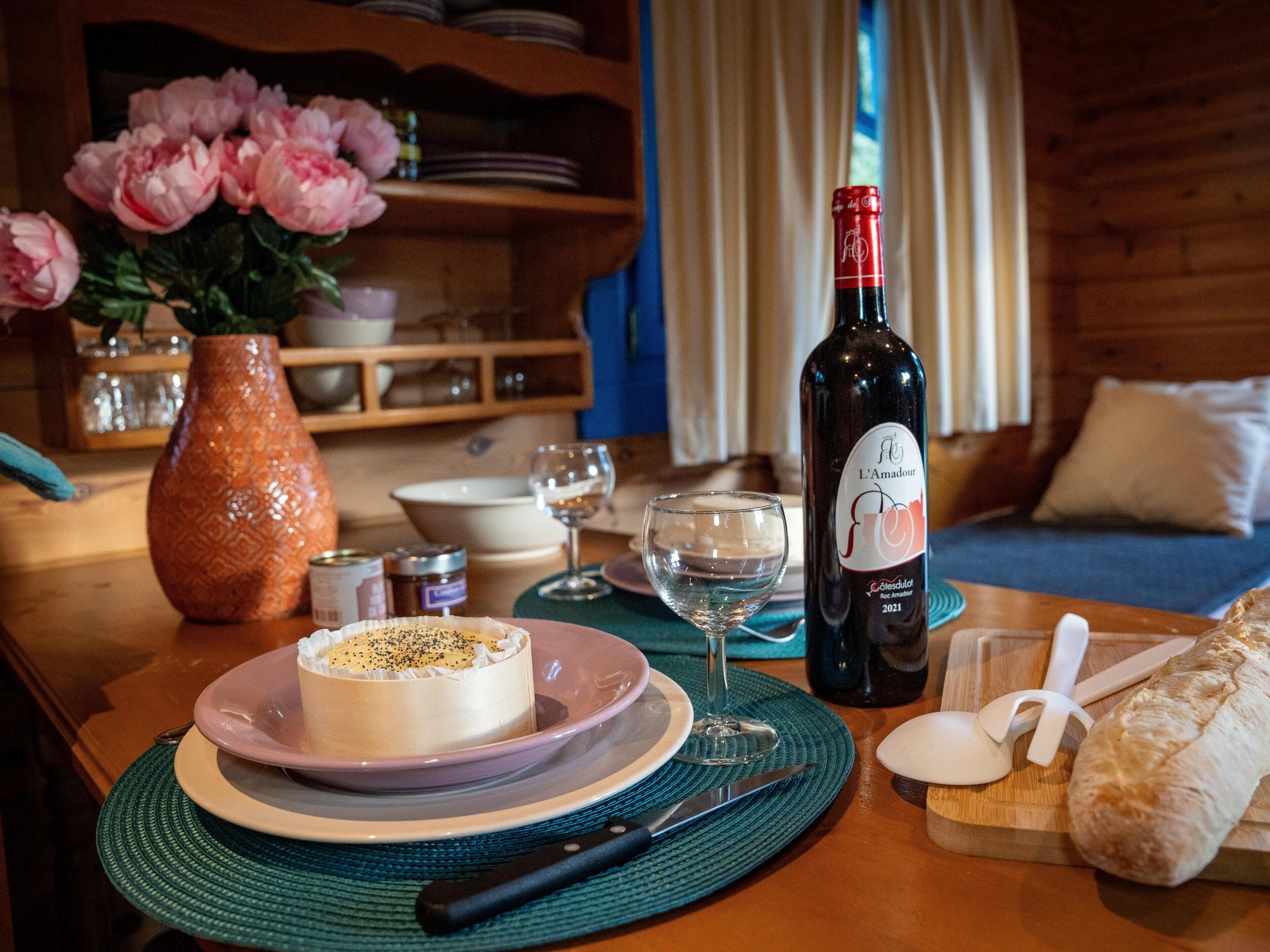 Een eettafel met een taart, een fles wijn, een brood en een vaas bloemen.