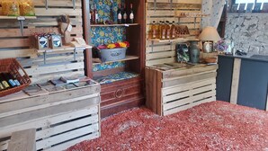 A rustic interior with wooden shelves displaying various items, a welcome sign, and a stone wall. - Roulottes du Petit Gouffre de Padirac (Padirac)