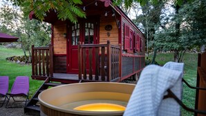 A wooden cabin with a porch, a hot tub, and purple chairs. - Roulottes du Petit Gouffre de Padirac (Padirac)