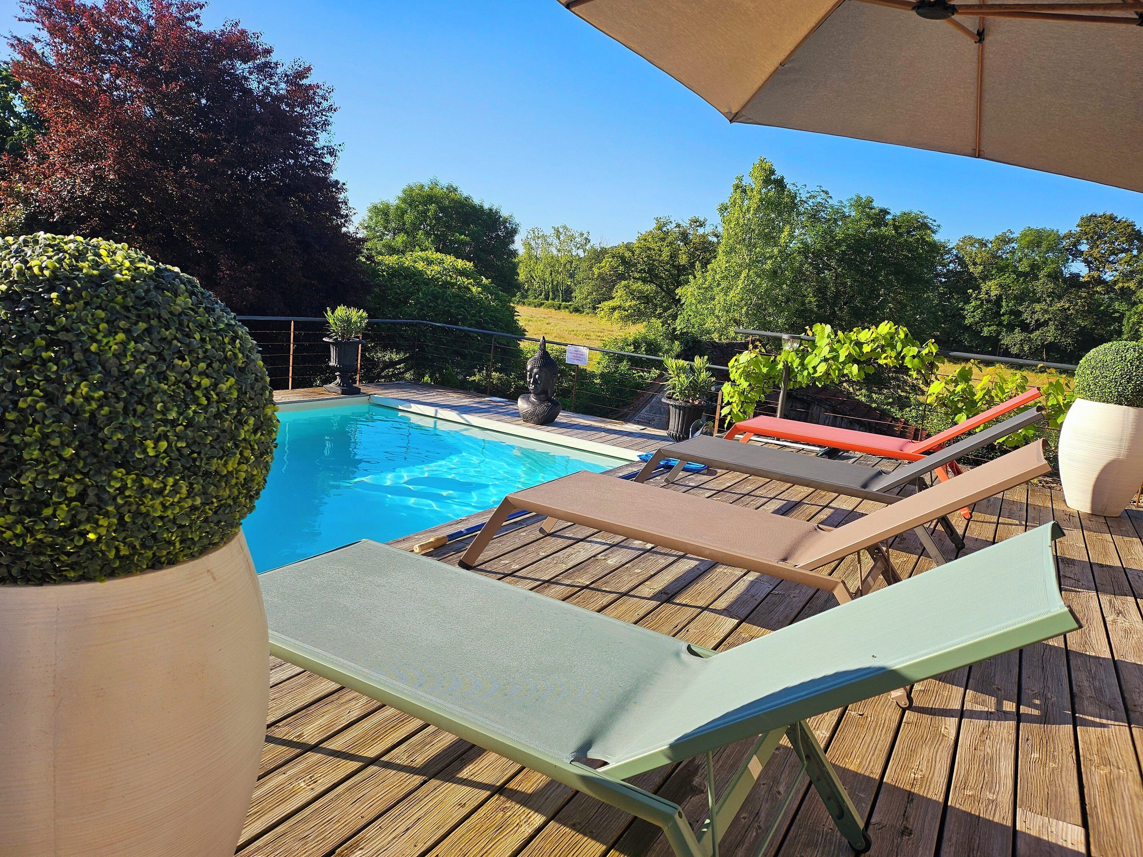 A wooden deck with a swimming pool, lounge chairs, and potted plants.
