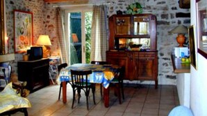 A rustic dining area with a wooden table and chairs, a stone wall, and a wooden ceiling.