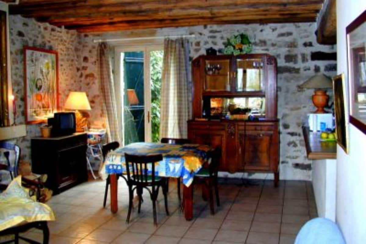 Un coin repas rustique avec une table et des chaises en bois, un mur en pierre et un plafond en bois.