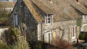 A stone building with a steep roof, a visible window, and a small door.