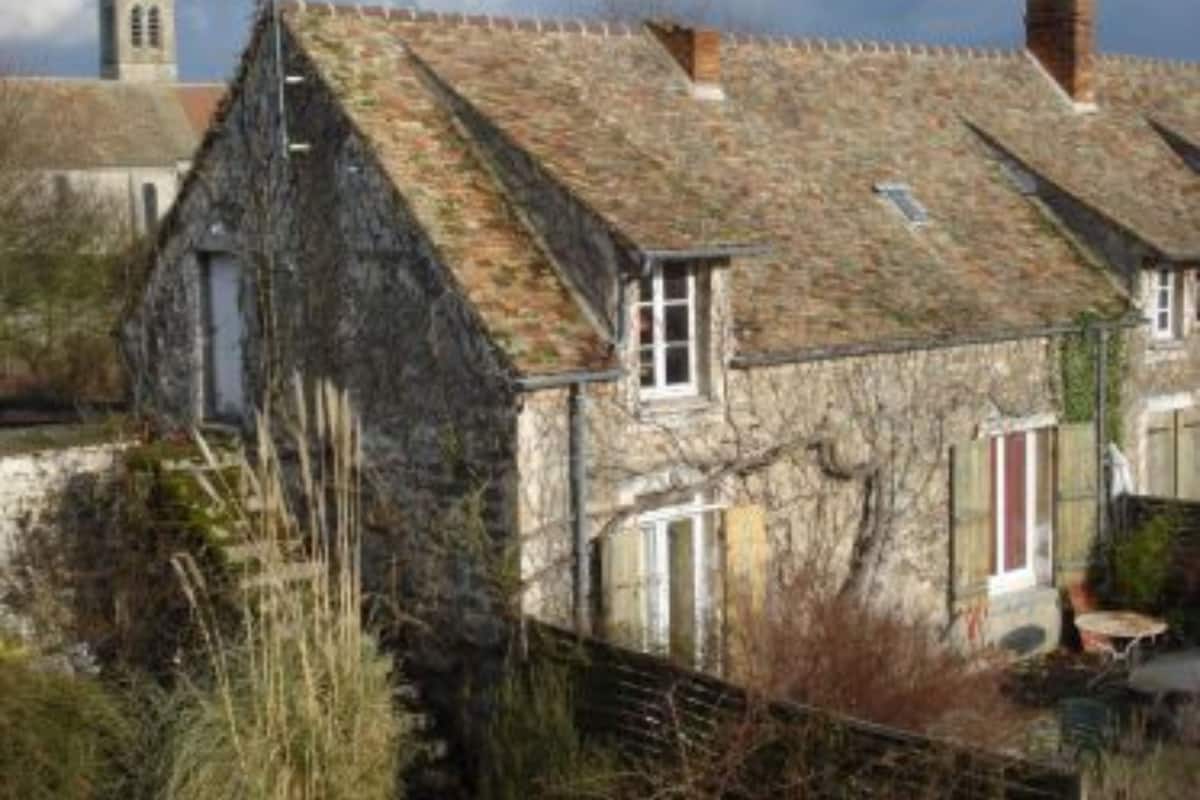 Un bâtiment en pierre avec un toit en pente, une fenêtre visible et une petite porte.