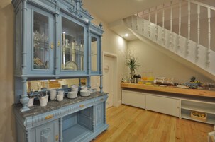 Una cocina con un armario azul, encimera de madera y una escalera con barandilla blanca.