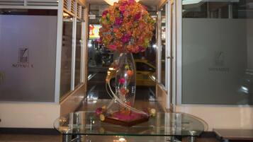 A lobby with a glass table, a chandelier, and a floral arrangement.