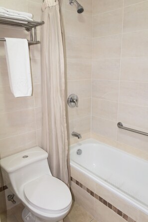 A bathroom with a toilet, a bathtub, and a shower curtain. - Hotel Novalux (Ambato)