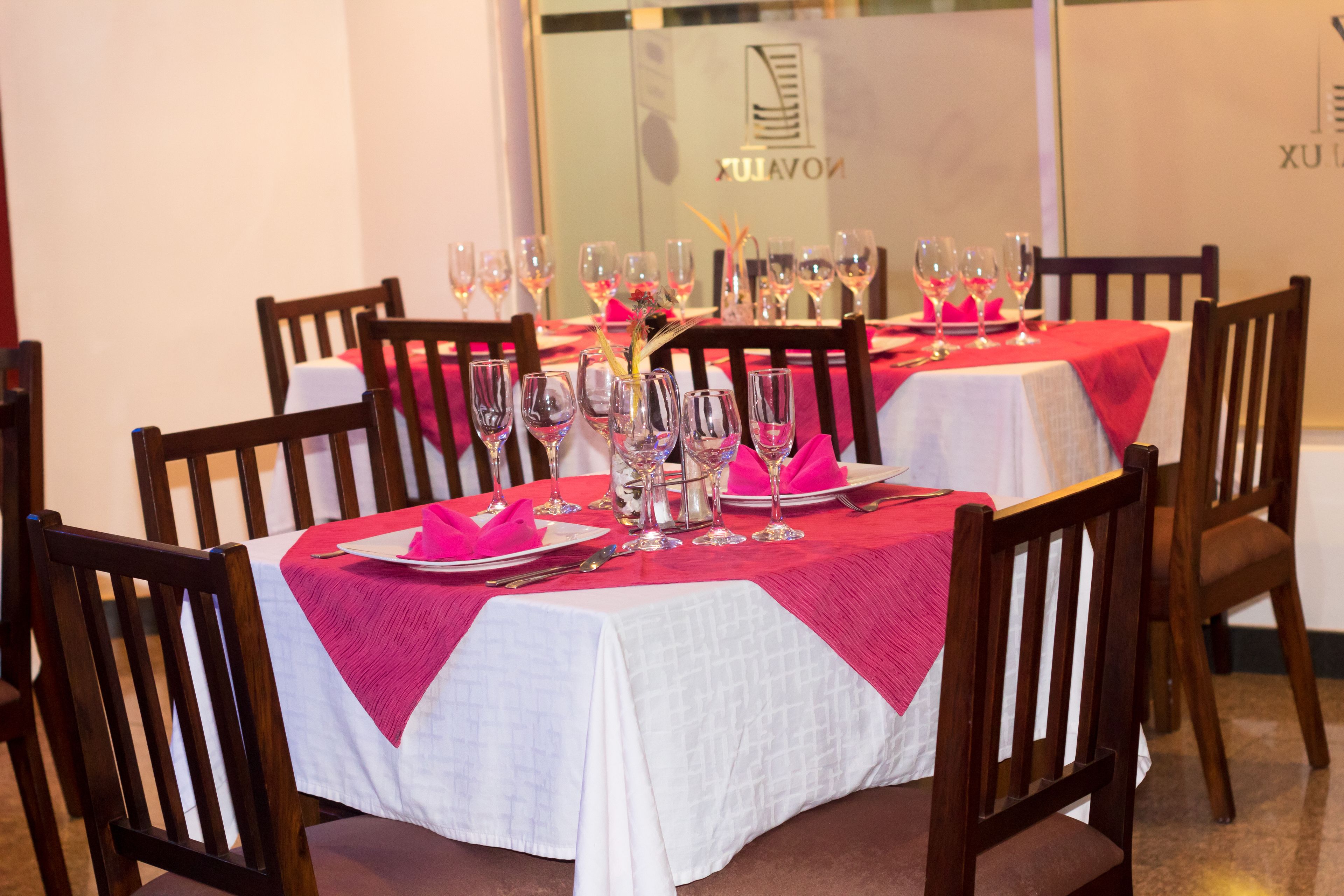 A dining area with tables set for a meal, featuring white tablecloths and red napkins.