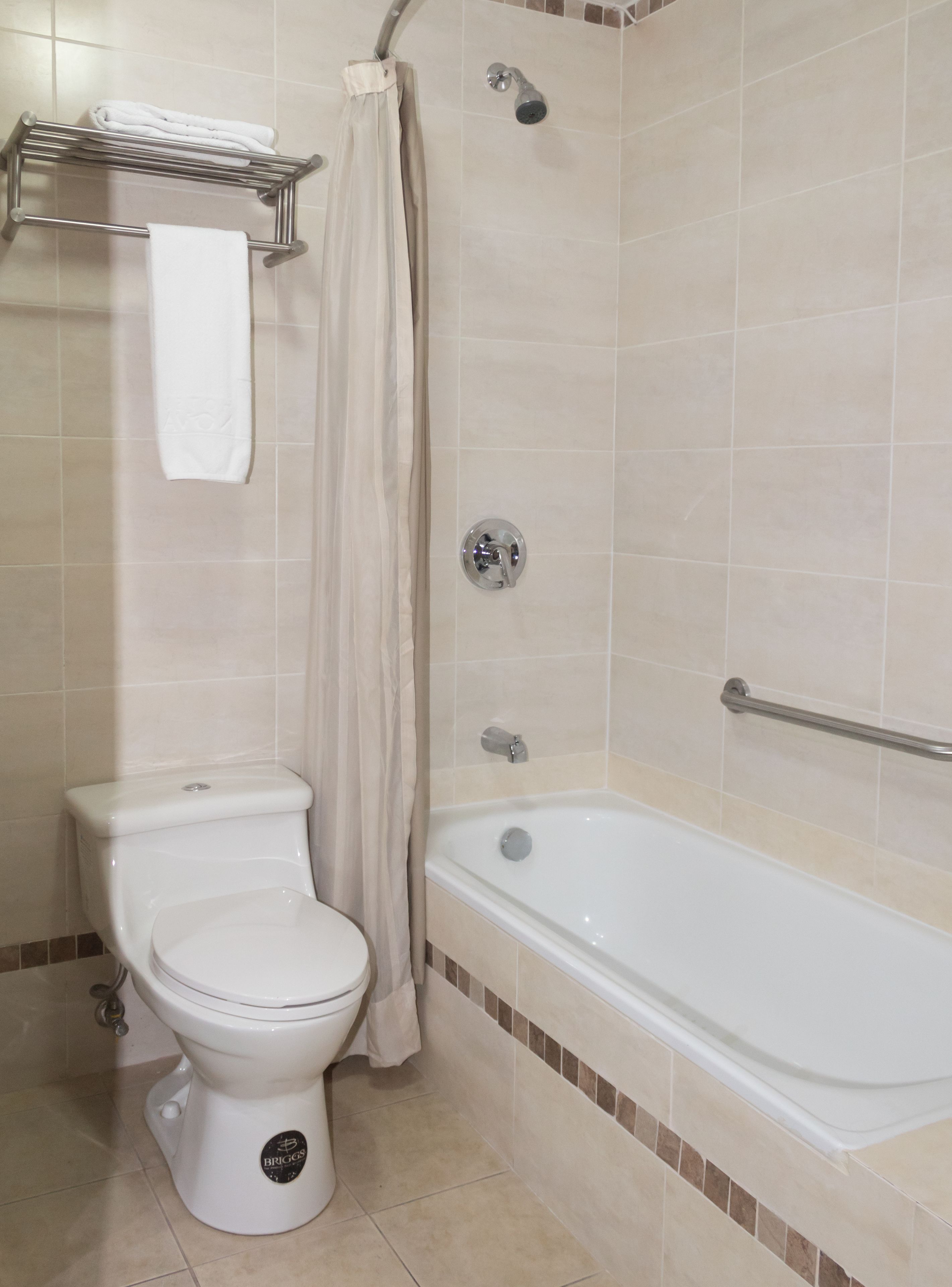 A bathroom with a toilet, a shower with a curtain, and a bathtub.