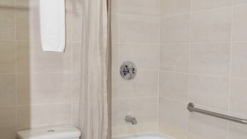 A bathroom with a toilet, a shower with a curtain, and a bathtub.