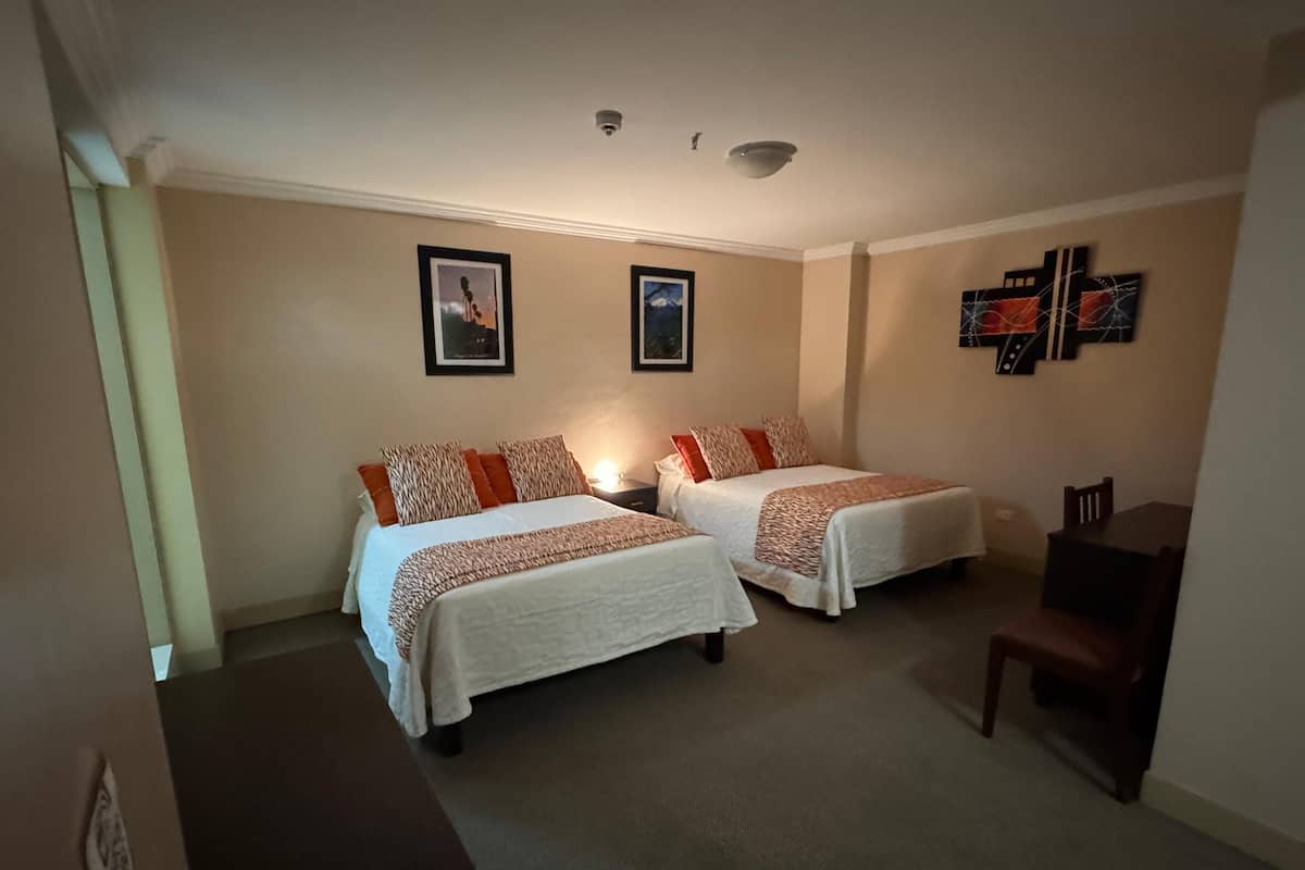 Ein Hotelzimmer mit zwei Betten, einem Schreibtisch und einem Stuhl.