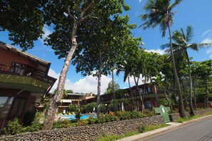 A resort with multiple-story buildings, a swimming pool, and lush greenery including palm trees. - Mar Arena 27 Apartment (Jacó)