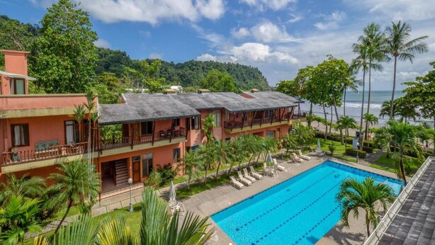 A hotel with a swimming pool, multiple balconies, and a view of the ocean. - Mar Arena 27 Apartment (Jacó)