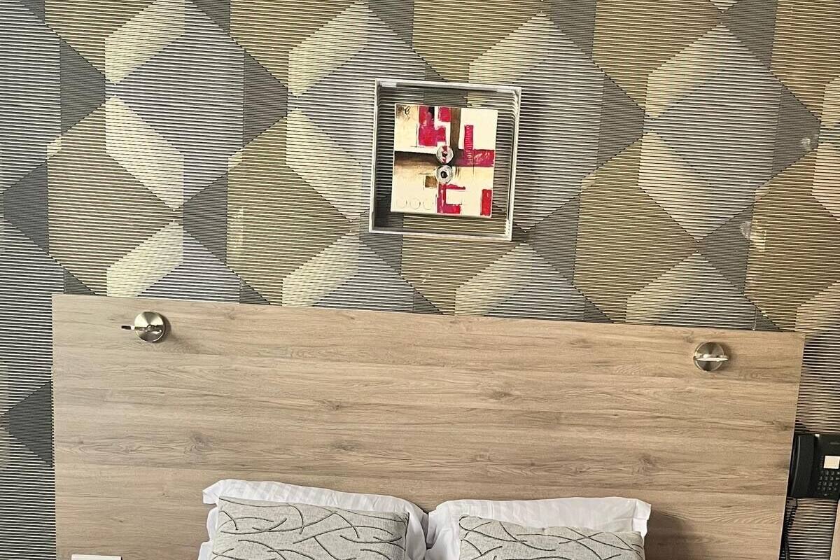 A neatly made bed with a swan-shaped towel, two patterned pillows, and a wooden headboard.