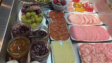 Una barra de buffet con diversos alimentos, entre ellos frutas, quesos, carnes y salsas.