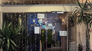 A hotel entrance with a glass door, illuminated by string lights, and a welcome mat. - Hôtel L'Univers (Chatellerault)