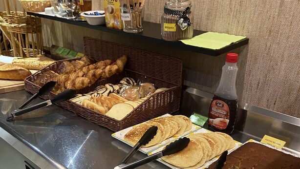 A buffet counter with various food items, including pastries, bread, and a cake. - Hôtel L'Univers (Chatellerault)
