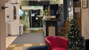 A hotel lobby with a Christmas tree, seating area, and a reception desk. - Hôtel L'Univers (Chatellerault)