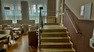 Un vestíbulo de hotel con una escalera, una zona de estar y vistas al exterior a través de amplias ventanas.
