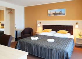 Una habitación de hotel con una cama grande, una silla, un escritorio y una mesita de noche.
