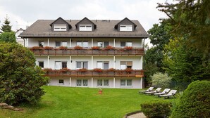 Un hotel de varios pisos con un césped bien cuidado, un área de estar al aire libre y un jardín.