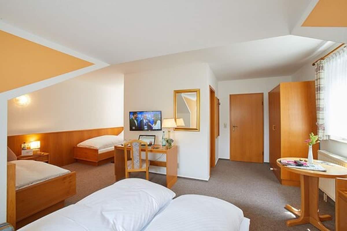 A hotel room with two beds, a desk with a chair, a television, and a mirror.