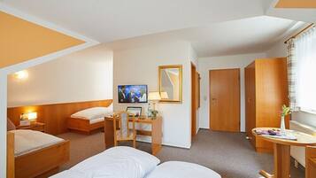 Quarto de hotel com duas camas, uma escrivaninha com cadeira, televisão e espelho.
