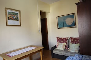 A room with a wooden desk, a sofa with patterned cushions, and two framed artworks on the walls. - Go house Arouche SP 804 (São Paulo)