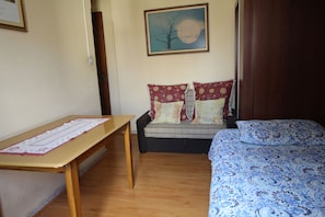 A bedroom with a wooden desk, a sofa with patterned cushions, and a bed with a blue patterned bedspread. - Go house Arouche SP 804 (São Paulo)