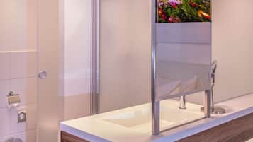 Un baño moderno con un mueble de tocador de madera, cabina de ducha de vidrio y un espejo grande.