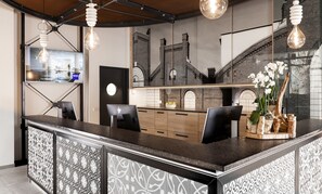 A modern bar area with a counter, seating, and decorative elements like a plant and a unique light fixture. - Dorint Hotel Düren (Dueren)
