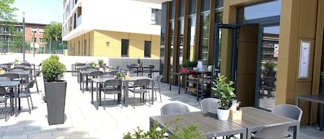 Un área de estar al aire libre con mesas y sillas, una planta en maceta y un letrero para Duron Bar & Grill.